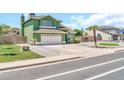 Green two-story home with a spacious driveway and mature landscaping adding curb appeal at 8871 W Maryland Ave, Glendale, AZ 85305