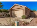 Tan single-story home with a two-car garage, desert landscaping and tile roof at 16365 N 138Th Ave, Surprise, AZ 85374