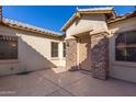 Inviting front patio with textured concrete, stone pillars and trim, with a secure front door at 16758 W Apache St, Goodyear, AZ 85338