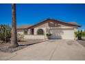 Exterior showcasing a two-car garage, arched windows, desert landscaping, and a long driveway at 17244 N 36Th Ln, Glendale, AZ 85308