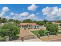 Charming single-story home with a red tile roof, mature trees and an gated paved driveway at 18132 E Vencino St, Gilbert, AZ 85298