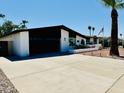 Charming single-story home with a brick exterior, dark garage door, palm trees and desert landscaping at 1941 E Ellis Dr, Tempe, AZ 85282