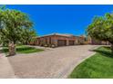 Beautiful home featuring an oversized three-car garage and stylish paver driveway, complemented by green grass at 24348 S 201St Ct, Queen Creek, AZ 85142
