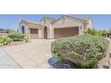 Beige stucco home with tile roof, two-car garage, driveway, and desert landscaping at 27413 W Tonopah Dr, Buckeye, AZ 85396