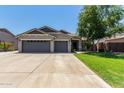 Attractive home with a three-car garage, wide driveway, manicured lawn, and mature trees in a residential neighborhood at 34970 N Spur Cir, San Tan Valley, AZ 85144