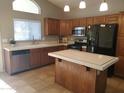 Bright kitchen boasts wooden cabinets, stainless appliances, a central island and tile flooring at 351 S Apache Dr, Chandler, AZ 85224