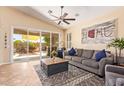 Bright living room with a ceiling fan, a comfortable sofa, and sliding glass doors to the patio at 3823 E Kroll Dr, Gilbert, AZ 85234