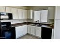 Bright kitchen with white cabinets, black appliances, a stainless steel sink, and a window at 43890 W Bedford Dr, Maricopa, AZ 85138