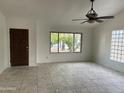Bright living room with tile flooring, ceiling fan, and large window overlooking the front yard at 8117 W Dreyfus Dr, Peoria, AZ 85381