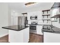 Bright kitchen featuring stainless steel appliances, a center island with granite countertop, and open wooden shelving at 1350 S Greenfield Rd # 1166, Mesa, AZ 85206