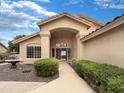 Inviting home featuring an arched entryway with decorative landscaping and a charming fountain at 14235 W Shawnee Trl, Surprise, AZ 85374