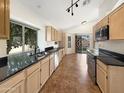 Spacious kitchen with sleek black countertops, modern appliances, and a view to the back yard at 14235 W Shawnee Trl, Surprise, AZ 85374