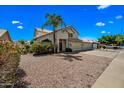Front exterior view of the home showing the desert landscaping, three-car garage and palm tree at 1638 N Avoca --, Mesa, AZ 85207