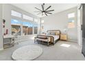 Sunlit primary bedroom with large windows, a cozy seating area, and a stylish ceiling fan, creating a serene retreat at 21391 W Mariposa St, Buckeye, AZ 85396