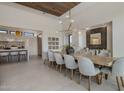 Dining room with a large wooden table, seating for ten, and a modern light fixture in an open concept space at 24863 N 103Rd Way, Scottsdale, AZ 85255