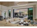 Open-concept living area with modern decor, statement lighting, and sliding glass doors to the backyard at 24863 N 103Rd Way, Scottsdale, AZ 85255