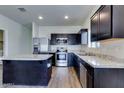 Modern kitchen with dark wood cabinets, stainless steel appliances, and a center island with granite countertops at 25602 W Coles Rd, Buckeye, AZ 85326