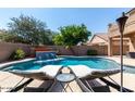 A luxurious backyard oasis featuring a sparkling pool with a waterfall feature and lounge chairs at 3693 E Sparrow Pl, Chandler, AZ 85286