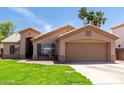 Single-story home with a desert landscape, two-car garage, and shaded front entry at 423 W Century Ct, Gilbert, AZ 85233