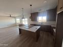 Open kitchen featuring an island, pendant lighting, wood cabinets, granite countertops, and a large window at 11650 N Abel Pl, Florence, AZ 85132