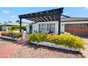 Close-up of a home's front porch with a pergola and seating, surrounded by colorful flowers at 13207 N 55Th Ave, Glendale, AZ 85304
