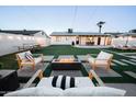 Spacious backyard featuring a modern fire pit, outdoor seating, putting green and manicured lawn at 2023 N 79Th Pl, Scottsdale, AZ 85257