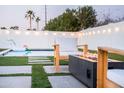Backyard featuring modern fire pit, lounge chair, pool and lush landscaping creating a perfect oasis at 2023 N 79Th Pl, Scottsdale, AZ 85257