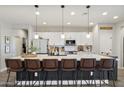 Modern kitchen features white cabinets, a large quartz countertop island, and pendant lighting above barstool seating at 5871 N 187Th Ln, Litchfield Park, AZ 85340