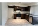 Bright kitchen featuring tile floors, stainless steel appliances, and dark wood cabinets at 6605 N 46Th Ln, Glendale, AZ 85301