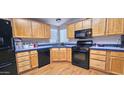 Traditional kitchen with wooden cabinets, black appliances, and blue-tiled backsplash at 8902 E Baltimore St, Mesa, AZ 85207