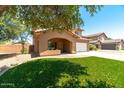 Inviting two-story home featuring an arched porch, lush lawn and mature shade tree at 1250 E Canyon Creek Dr, Gilbert, AZ 85295