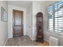 Welcoming foyer features tile flooring, a wooden front door, and abundant natural light at 16165 W Vale Dr, Goodyear, AZ 85395