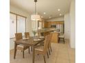 Cozy dining area with views into kitchen, tile flooring, and modern light fixture at 17617 W Corrine Dr, Surprise, AZ 85388