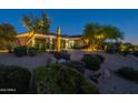 Beautiful desert landscaping enhances this home with a circular driveway and attached garages at dusk at 19947 N 94Th Way, Scottsdale, AZ 85255