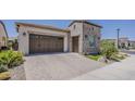 View of the home's exterior highlighting the 2-car garage and brick driveway at 35486 N Morello Dr, Queen Creek, AZ 85140