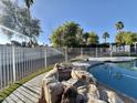 Relaxing backyard pool with rock feature, turf and view of palm trees at 4838 W Christine Cir, Glendale, AZ 85308