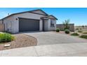 Lovely single-story home boasts a grey garage, desert landscaping, and a spacious paved driveway at 6145 S Adelle --, Mesa, AZ 85212