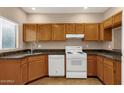 Functional kitchen featuring granite countertops, wood cabinets, and modern white appliances, creating a cozy cooking space at 7101 W Beardsley Rd # 1502, Glendale, AZ 85308