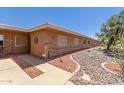 Tan home featuring desert landscaping with brick accents and neutral-toned exterior at 10860 W Buccaneer Dr, Sun City, AZ 85351