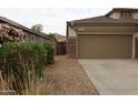 Side view of the house with a two-car garage and desert landscaping at 14977 W Charter Oak Rd, Surprise, AZ 85379