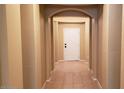 Inviting hallway with arched entryways featuring neutral color palette and tiled flooring at 14977 W Charter Oak Rd, Surprise, AZ 85379
