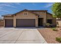Single-story home with a three-car garage, complemented by desert landscaping and stone accents at 17531 W Fetlock Trl, Surprise, AZ 85387