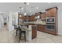A spacious kitchen features dark wood cabinets, granite countertops, a center island with seating, and stainless steel appliances at 2466 E Aris Dr, Gilbert, AZ 85298