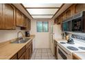 Functional kitchen with vintage wood cabinetry, light countertops, and modern appliances at 3131 W Cochise Dr # 144, Phoenix, AZ 85051