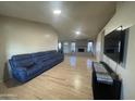 Spacious living room with light wood floors, blue sofa, fireplace, and TV; ideal for relaxation and entertainment at 405 E Providence Dr, Casa Grande, AZ 85122