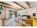 Open-concept living room with beamed ceiling, modern lighting, and seamless flow to the kitchen and outdoor patio at 4050 S Thistle S Dr, Chandler, AZ 85248