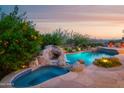 Beautiful pool featuring a rock waterfall, spa, and lush landscaping, creating a private oasis at 5921 E Leisure Ln, Carefree, AZ 85377