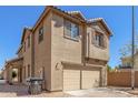 Two-story tan home featuring a two car garage and desert landscaping in front at 823 E Agua Fria Ln, Avondale, AZ 85323