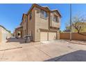 Two-story tan home featuring a two car garage and desert landscaping in front at 823 E Agua Fria Ln, Avondale, AZ 85323