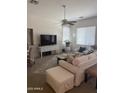 Bright living room featuring neutral decor, a ceiling fan, and comfortable white furnishings at 14991 W Shaw Butte Dr, Surprise, AZ 85379